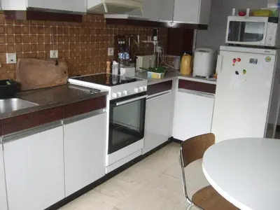 a kitchen with white appliances and a table in it at Bij het station van Drongen in Ghent