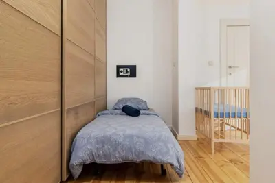 a bedroom with a bed and a wooden wall at Cosy EU Apartment - Central, Parking, Terrace in Brussels