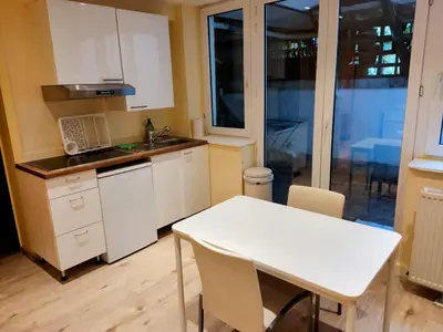 a kitchen with white cabinets and a white table and chairs at Modern half-basement 1BR near Montgomery & VUB in Brussels