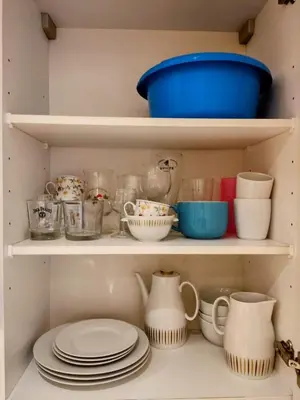 a cupboard filled with dishes and bowls and plates at Modern half-basement 1BR near Montgomery & VUB in Brussels