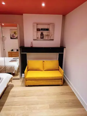 a yellow couch in a room with a bedroom at Modern half-basement 1BR near Montgomery & VUB in Brussels