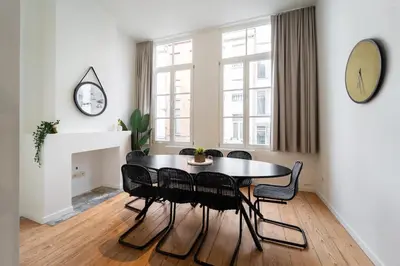 a dining room with a table and chairs and a clock at Spacious 7-Person House in the Heart of Antwerp in Antwerp
