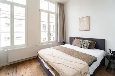 a bedroom with a bed with white walls and windows at Spacious 7-Person House in the Heart of Antwerp in Antwerp