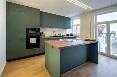 a kitchen with green cabinets and a wooden floor at Brussels Louise Design residence in Brussels