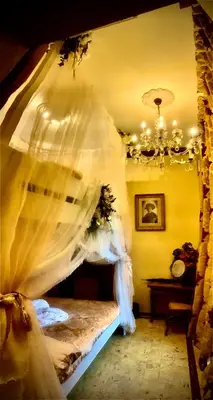 a bedroom with a bed with white curtains and a chandelier at Casa Lucinda in Ghent