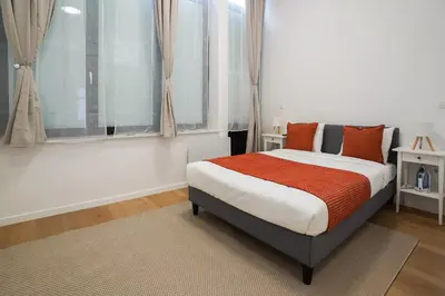 a bedroom with a bed with orange pillows and a window at Appartment St guidon 1 in Brussels