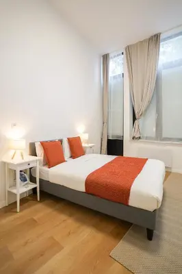 a white bedroom with a bed and a window at Appartment Vaillance 2 in Brussels