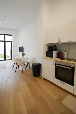 a kitchen with white appliances and a table and chairs at Appartment Vaillance 2 in Brussels