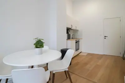 a white table and chairs in a white kitchen at Appartment Vaillance 2 in Brussels