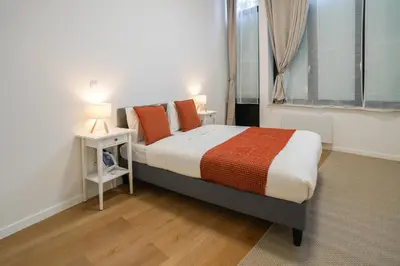 a bedroom with a bed with orange pillows and a window at Appartment Vaillance 2 in Brussels