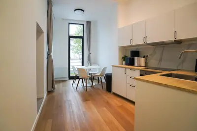 a kitchen with white cabinets and a table with chairs at Appartment Wayez 3 in Brussels