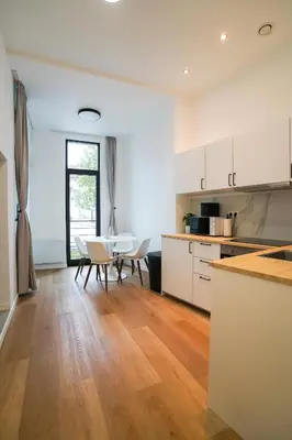 a kitchen with white cabinets and a table and chairs at Appartment Wayez 3 in Brussels
