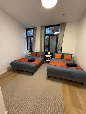 two beds in a room with two windows at Appartment Wayez 3 in Brussels