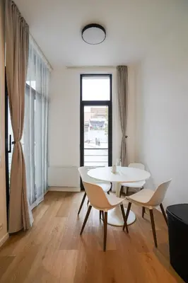 a white dining room with a table and chairs at Appartment Wayez 3 in Brussels