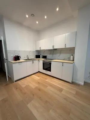 an empty kitchen with white cabinets and a wooden floor at Appartment Astrid 4 in Brussels