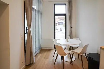 a white table and chairs in a room with a window at Appartment Janson 5 in Brussels