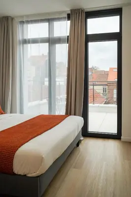 a bedroom with a bed and a large window at Appartment Janson 5 in Brussels