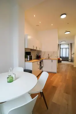 a white kitchen with a white table and chairs at Appartment Janson 5 in Brussels