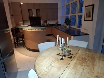 a kitchen with a wooden table with white chairs at Brussels' Premier Parkside Residence in Brussels