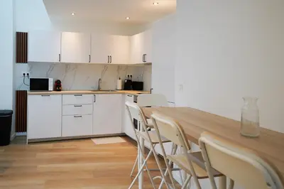 a kitchen with a long table and white cabinets at Appartment Douvres 7 in Brussels
