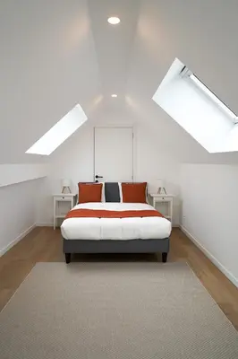 a white bedroom with a bed in a attic at Appartment Douvres 7 in Brussels
