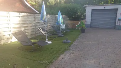 two lawn chairs and umbrellas in a yard at Beach House in Brasschaat