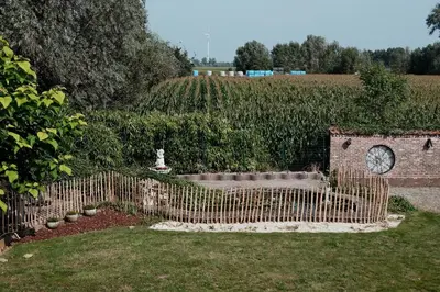 a garden with a fence and a clock in a field at Vakantiewoning Welle Weg in Berlare