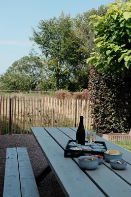 a picnic table with bowls of food and a bottle at Vakantiewoning Welle Weg in Berlare