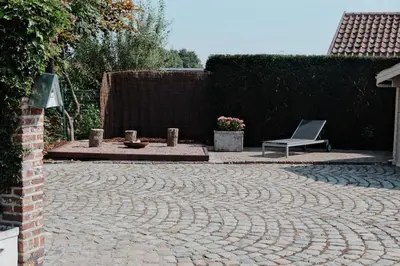 a stone patio with a chair and a bench at Vakantiewoning Welle Weg in Berlare