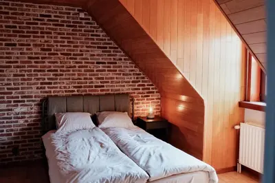 a bed in a room with a brick wall at Vakantiewoning Welle Weg in Berlare