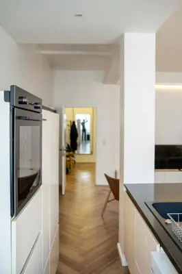 a kitchen with white walls and a wooden floor at Brussels South - Cosy Appartment in Brussels