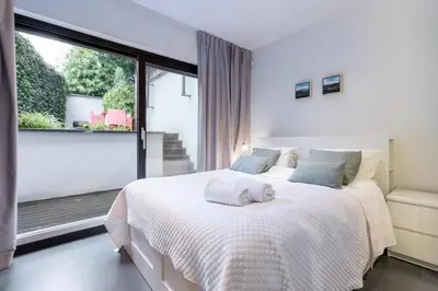 a bedroom with a white bed and a large window at Luxury Deluxe Garden Condo in Brussels Centre in Brussels