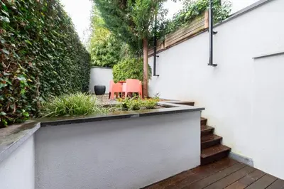 a garden with two red chairs and a fence at Luxury Deluxe Garden Condo in Brussels Centre in Brussels