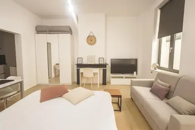a white living room with a couch and a tv at Toison d'Or Apartment in Brussels