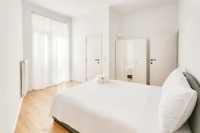 a white bedroom with a white bed and a window at Cozy Brabanconne apartment in Brussels