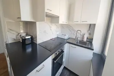 a kitchen with white cabinets and a black counter top at Cozy Brabanconne apartment in Brussels