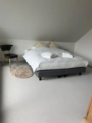 a bedroom with a bed with a chair and a chair at De Kempische Hoef in Westerlo
