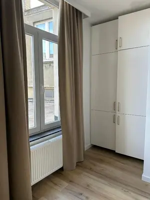 a room with a large window and white cabinets at 5- Nid lumineux 2 chambres au plein coeur d'Ixelles in Brussels