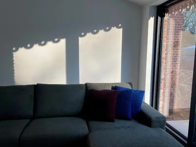 a couch with pillows sitting in a room with a window at Tampico, Holiday Home at river Schelde in Hamme