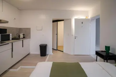 a white room with a bed and a kitchen at Malbeek 7 in Brussels