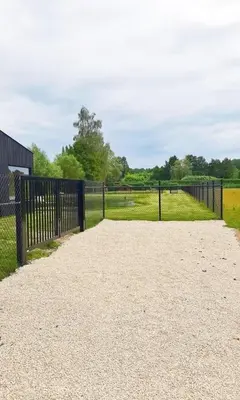 a gravel driveway with a fence and a field at Black Pearl in Hamme