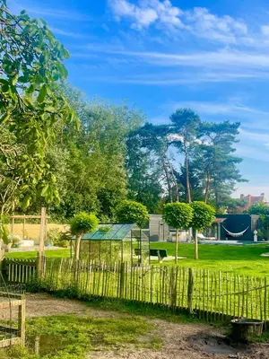 a fence in a park with trees and a building at Chambre d Amis in Lokeren
