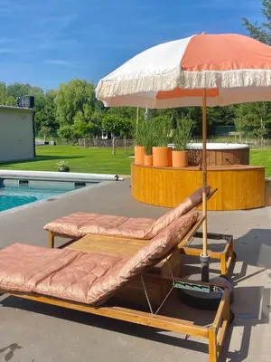 two beds with an umbrella next to a pool at Chambre d Amis in Lokeren