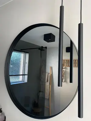 a round mirror hanging on a wall in a living room at Chambre d Amis in Lokeren