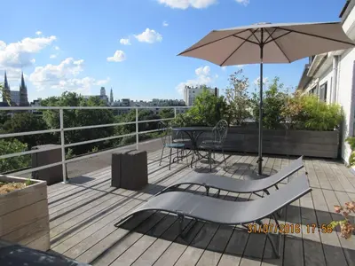 a deck with an umbrella and a table and a bench at Fuths Penthouse 55 in Antwerp