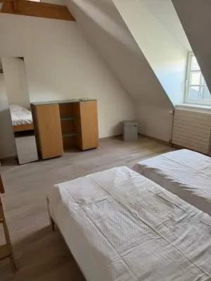 a attic bedroom with two beds and a desk at Oase in the City in Brussels