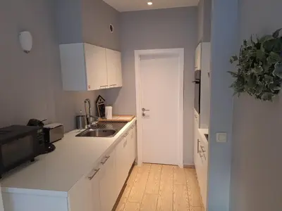 a kitchen with white cabinets and a sink and a refrigerator at Résidence des sables in Brussels