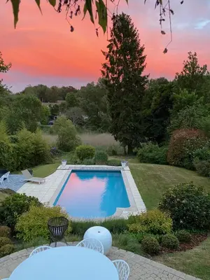 a swimming pool in a yard with a sunset at Maison d'hôte Yourehome 2 belles chambres à louer individuellement dans un écrin de verdure in La Hulpe