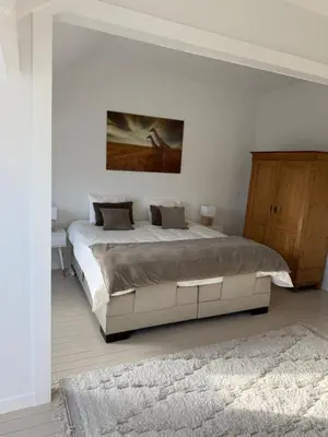 a bedroom with a large bed and a painting on the wall at Maison d'hôte Yourehome 2 belles chambres à louer individuellement dans un écrin de verdure in La Hulpe