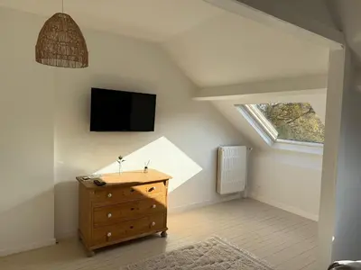 a attic room with a tv and a wooden dresser at Maison d'hôte Yourehome 2 belles chambres à louer individuellement dans un écrin de verdure in La Hulpe